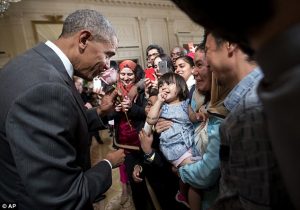 President Obama smells a rose given to him by one Muslim American family during the White House's first ever `Eid celebration on Thursday.