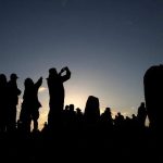Revellers-watch-the-sun-set-on-the-eve-of-the-Summer-Solstice-at-the-Stonehenge-stone-circle,-in-Amesbury,-June20
