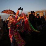 The sun rises as a reveller welcomes in the Summer Solstice at the Stonehenge stone circle, in Amesbury, Britain, June-21