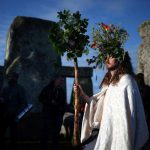 The sun rises as a reveller welcomes in the Summer Solstice at the Stonehenge stone circle, in Amesbury, Britain, June-21.