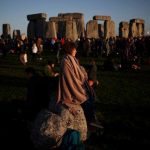 The sun rises as a reveller welcomes in the Summer Solstice at the Stonehenge stone circle, in Amesbury, June-21
