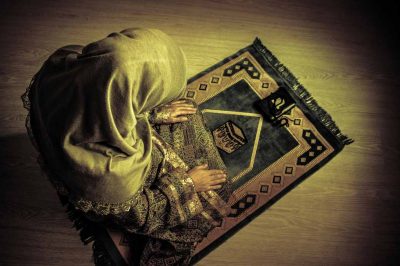 Muslim woman offering prayer on prayer mat