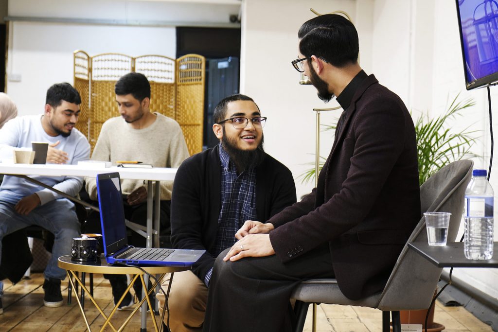 Faith community co-founders Adel Chowdhury, center, and Imam Shabbir Hassan, right, chat during a break in a session, Jan. 27, 2020, in the group’s new permanent space in London. RNS photo by Aysha Khan