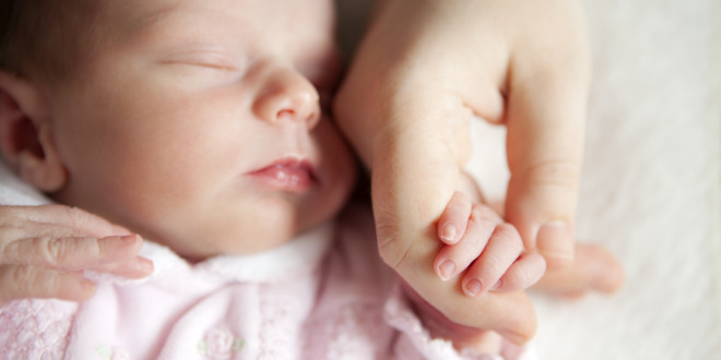 Newborn baby holding mother’s hand