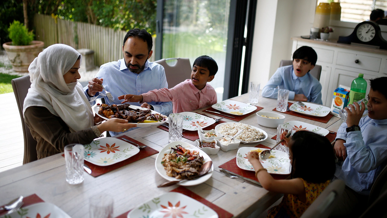 Muslim family at home eating food to mark the end of the month of Ramadan in Surbiton, London. [Image-REUTERS]