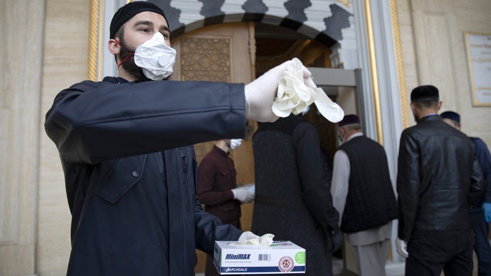 Volunteers in face masks handed out gloves at the entrance to the Heart of Chechnya Mosque in Grozny