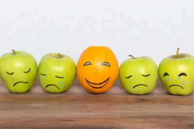 apples with drawn sad faces and an orange with a smile