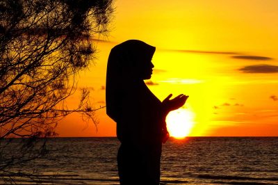 Silhouette of muslim woman praying to the god