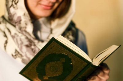 a girl in a mosque is holding a holy book