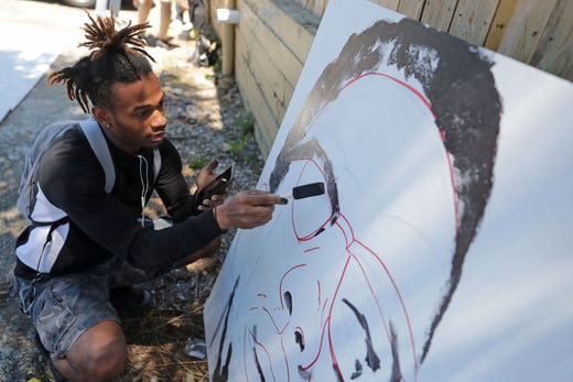 Mario Hamilton works on the outline of a Malcolm X face