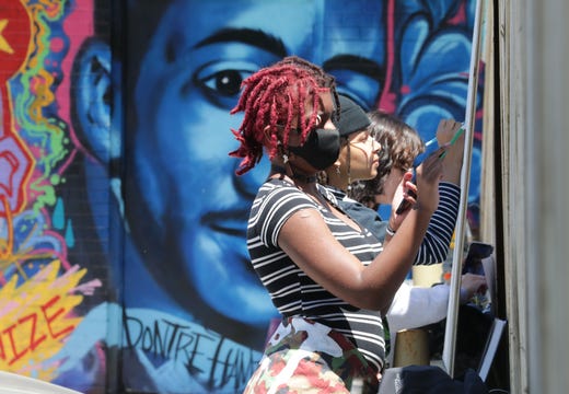 Aminah Green, left, works with others on a collective mural for Black Lives Matter
