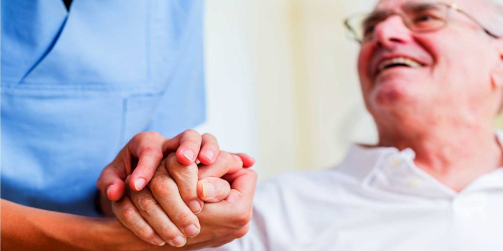 Nurse holding hand of senior man in rest home