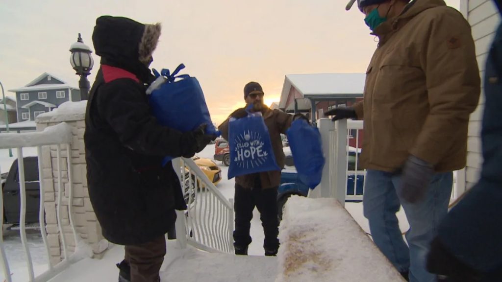 Nazim Awan of the Islamic Centre of Yellowknife hands off a couple warming kits for volunteers to bring into the local YWCA. (Graham Shishkov/CBC)
