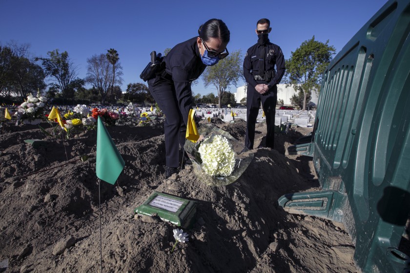 Two of Hashem Ahmad Alshilleh’s children, Rayah, left, and Mahmoud, both police officers, place flowers at their father’s grave at Westminster Memorial Park Mortuary.(Irfan Khan / Los Angeles Times)