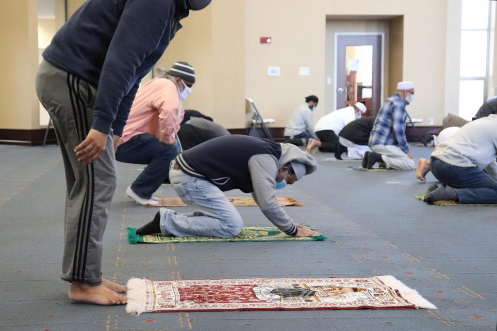 A man lays down a mat to join in prayer at Noor Islamic Cultural Center.CREDIT ADORA NAMIGADDE / WOSU