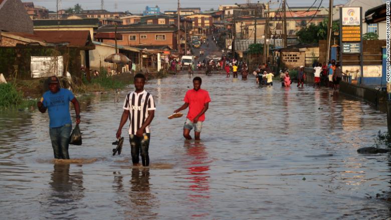 Residents wade through flooded Ige Road, in Aboru, Lagos, after a heavy downpour on July 6, 2020.