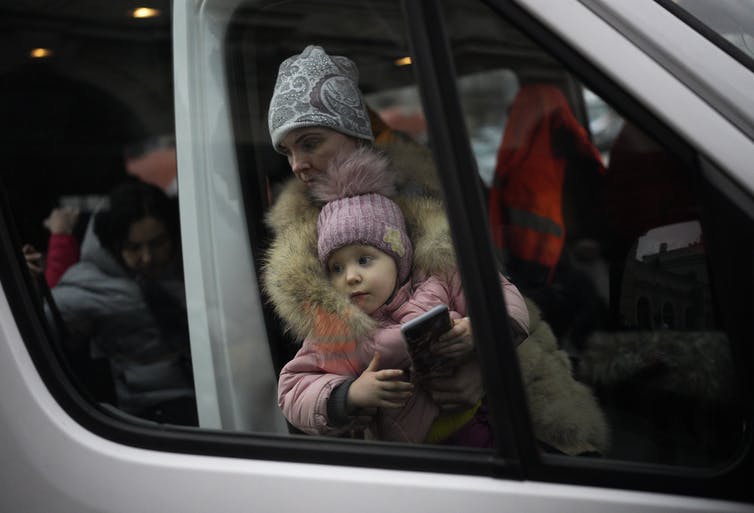 A woman and child, who have fled Ukraine, arrive at the train station in Przemysl, Poland, on March 8, 2022. AP Photo/Daniel Cole