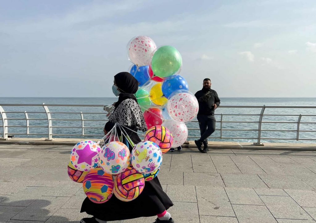 A woman carries balloons for sale as she walks along a seaside promenade
Photograph: Yara Abi Nader/Reuters