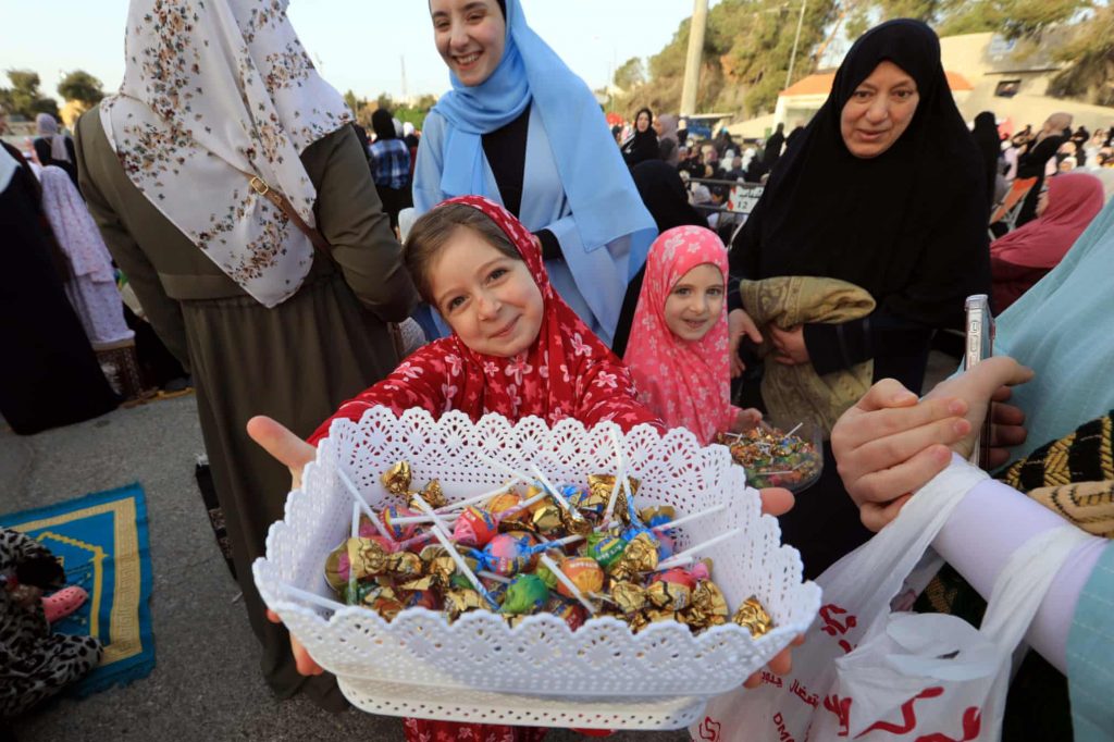 A girl distributes sweets in Amman, Jordan Photograph: Xinhua/Rex/Shutterstock