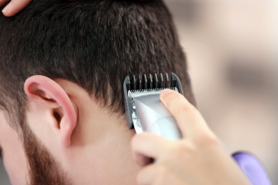 Hairdresser cutting hair with clipper-