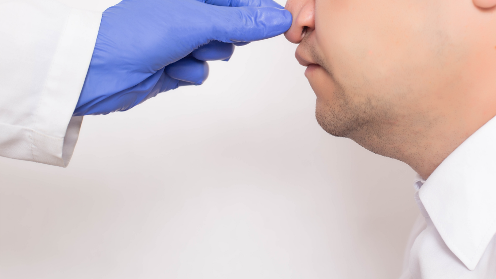 Doctor plastic surgeon checks a man’s nose before nose correction surgery