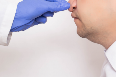 Doctor plastic surgeon checks a man’s nose before nose correction surgery