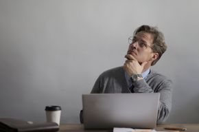 thoughtful male manager working on laptop in modern workplace