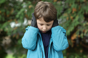 Autistic lonely Little Boy Covering His Ears Outdoors