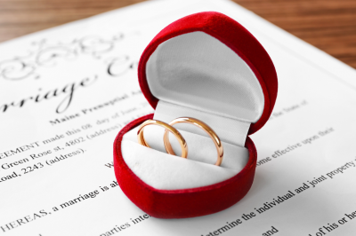 Red Box with Golden Wedding Rings on Marriage Contract