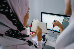 Woman in Pink Headscarf Stands in Front of Silver Imac