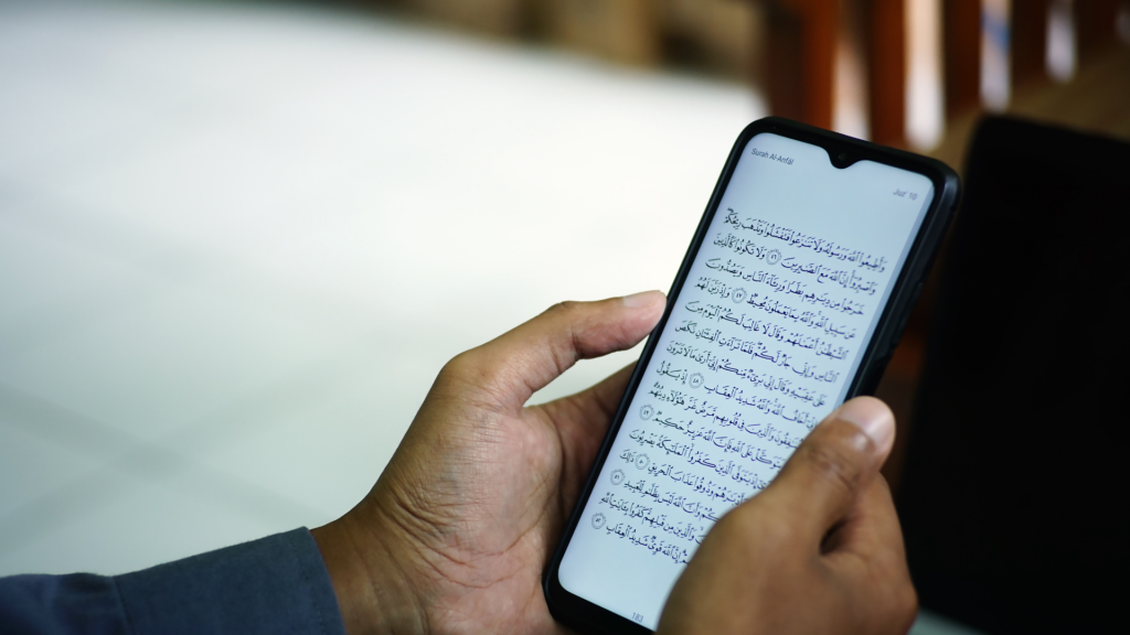 man hands holding quran on phone