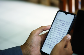 man hands holding quran on phone